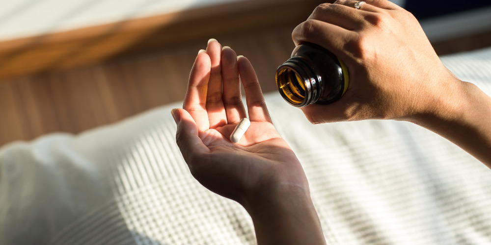 Person interested in wellness taking a vitamin from bottle - The PHA Group
