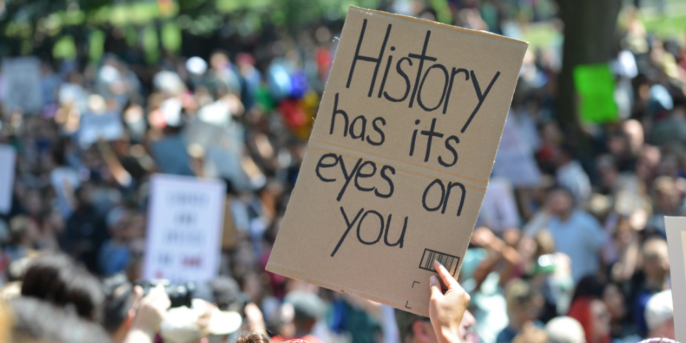Group protesting for class action communications holding a sign up - The PHA Group