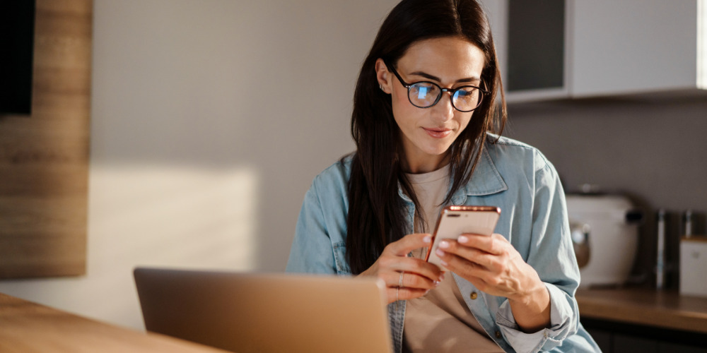 Woman on her phone researching GEO vs SEO - The PHA Group