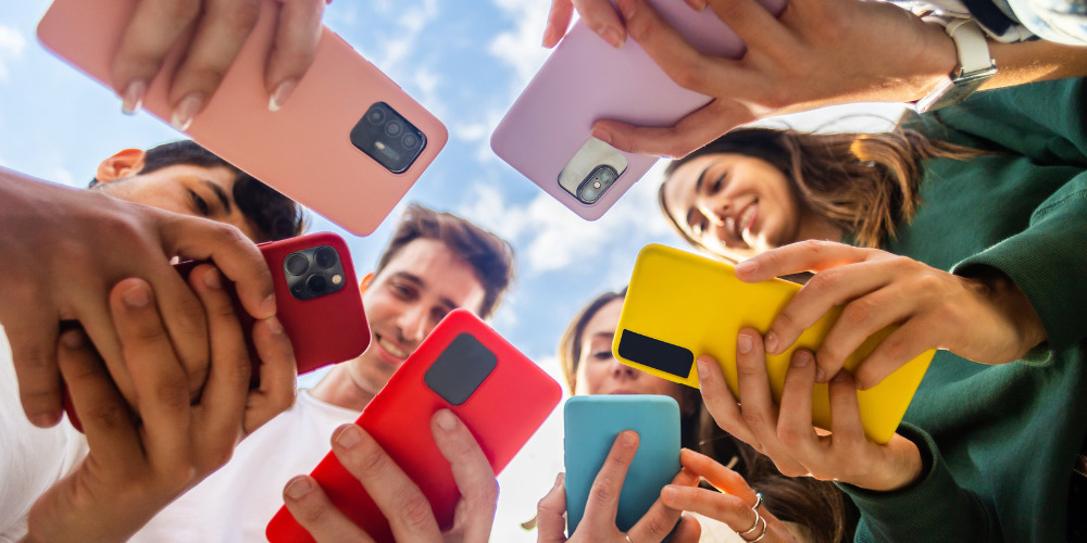 Group of people in a circle looking at their phones - The PHA Group