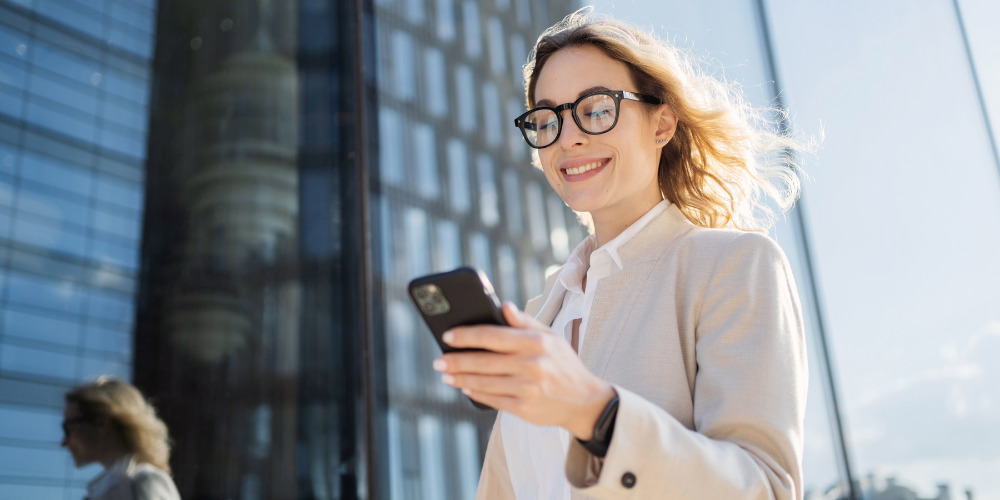 Business woman on her phone using AI-search with GEO integrated into digital strategy - The PHA Group