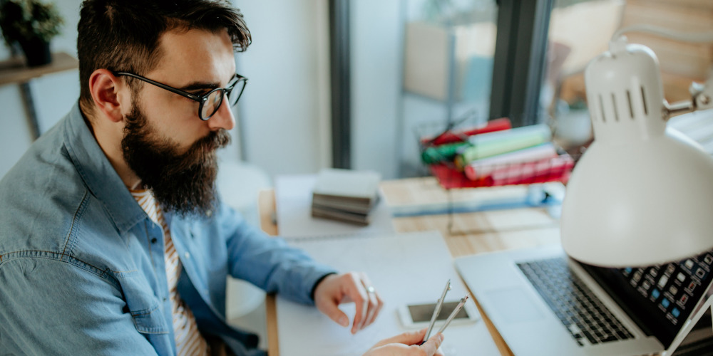 Man sitting at desk in front of computer thinking about corporate PR media coverage - The PHA Group