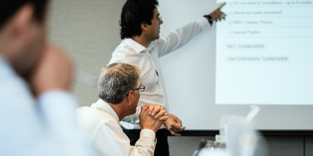 Man standing in front of projector describing benefits of corporate PR - The PHA Group