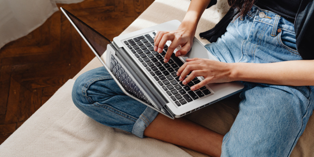 Girl sitting down with laptop and researching brand AI visibility on a laptop - The PHA Group