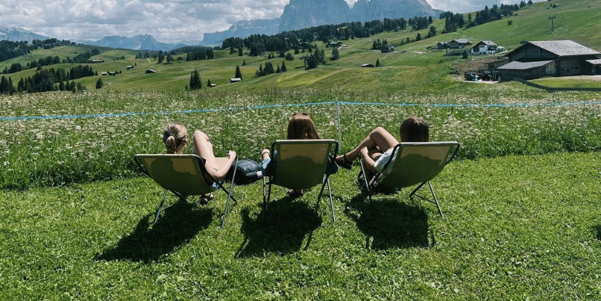 Consumer travel motivations led to 3 girls laying on deck chairs looking at green fields - The PHA Group