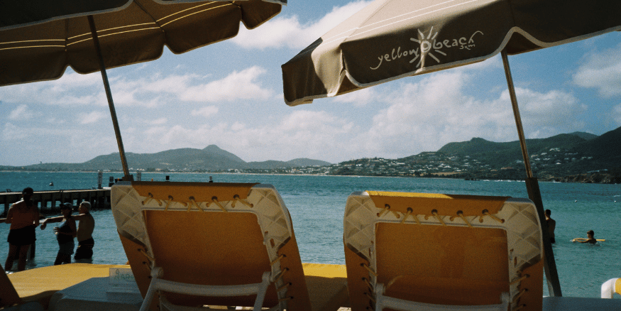 Two sun loungers with umbrellas facing the sea - The PHA Group