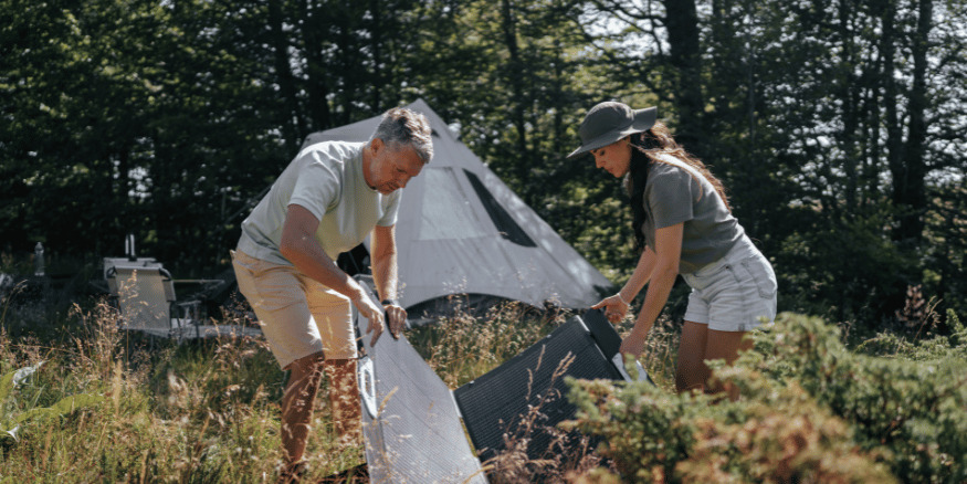 Couple in the woods setting up a tent to camp - The PHA Group